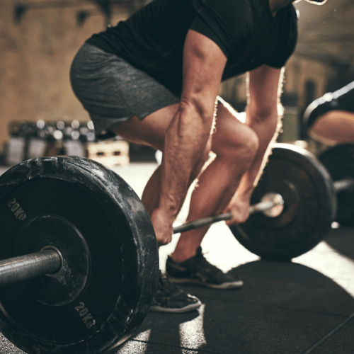 Person lifting a barbell in a gym setting, emphasizing strength training and personal fitness progress.