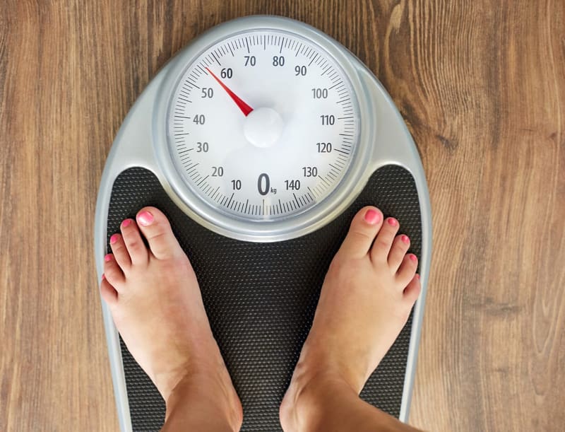 Feet on a weighing scale displaying weight measurement, symbolizing weight management and healthy lifestyle choices.